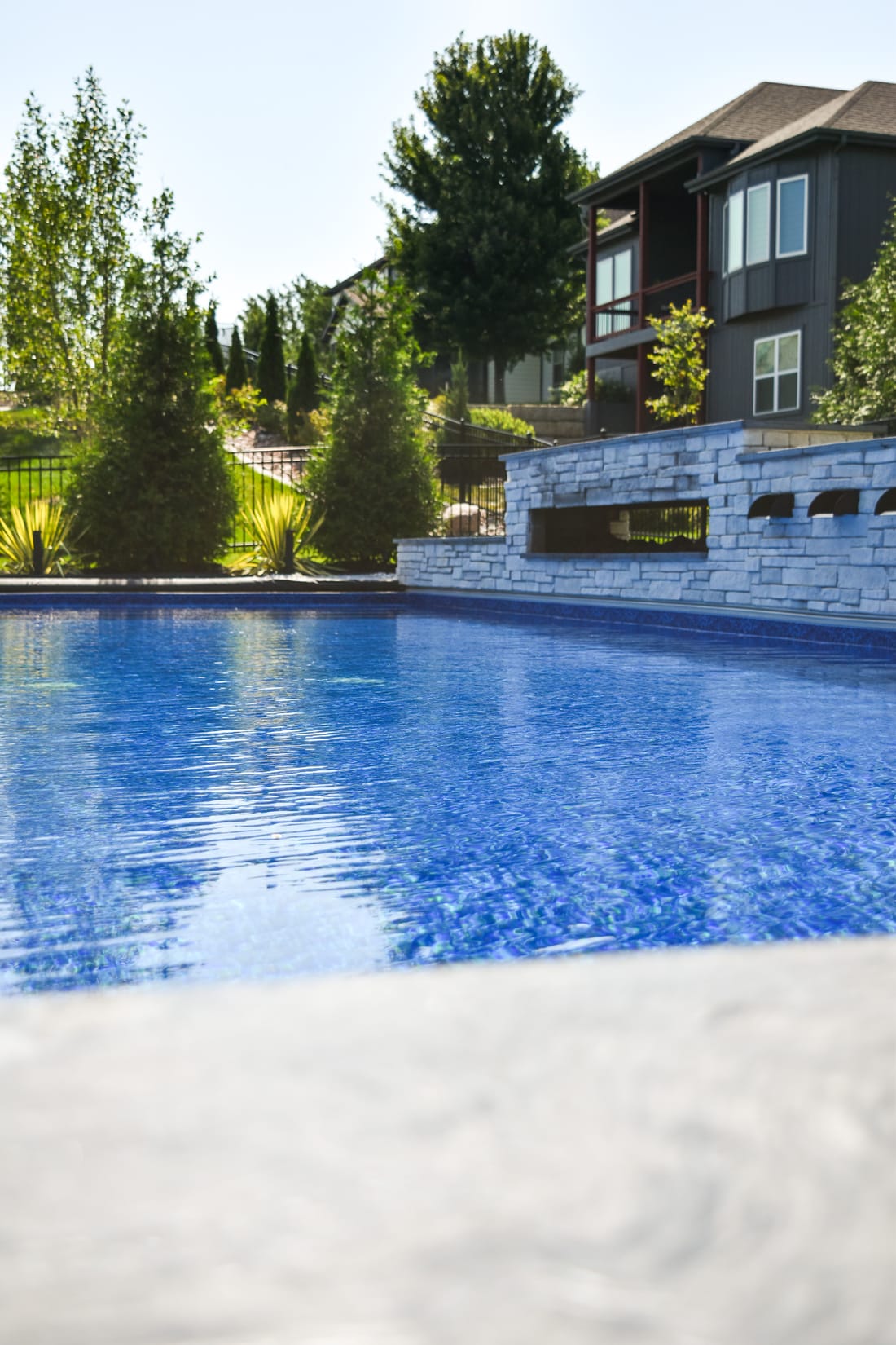Infinity-edge swimming pool overlooking a wooded backyard