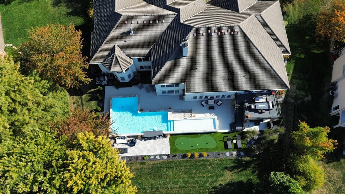 Aerial view of a backyard swimming pool and patio beside a home