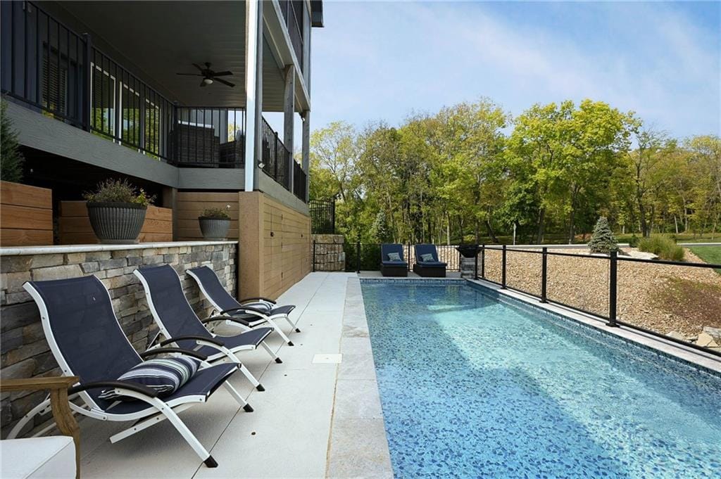 Lounge chairs lined along a long rectangular pool on a paver deck