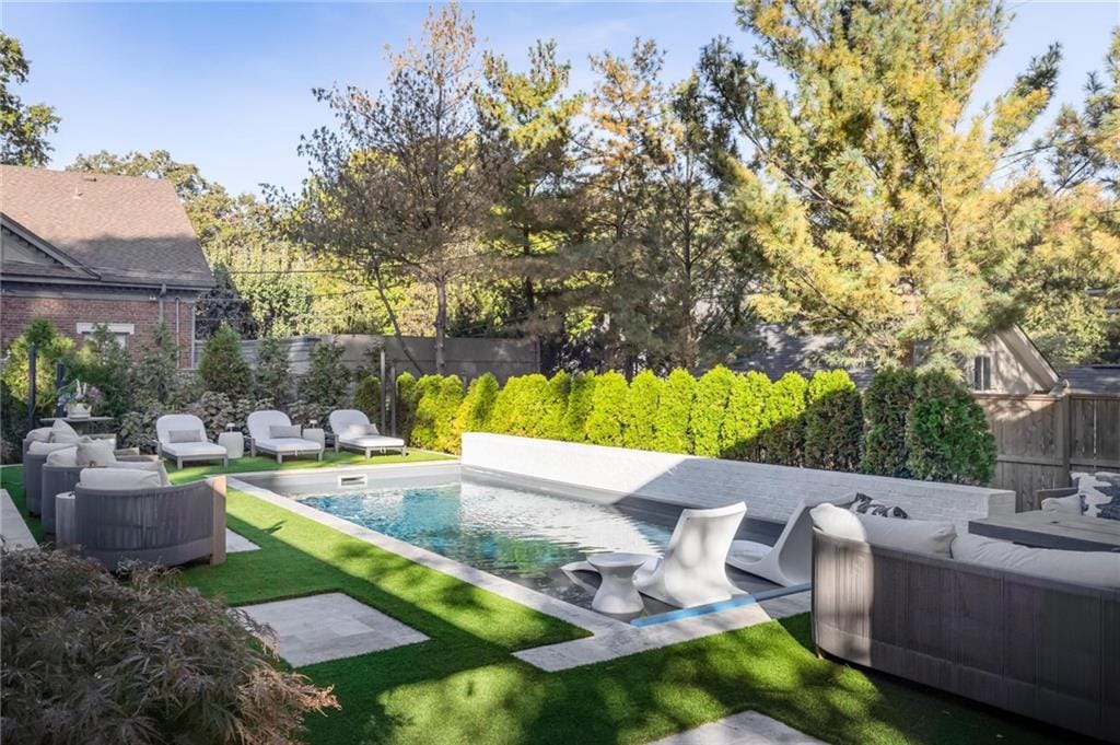 Landscaped backyard with a swimming pool, plantings, and patio seating