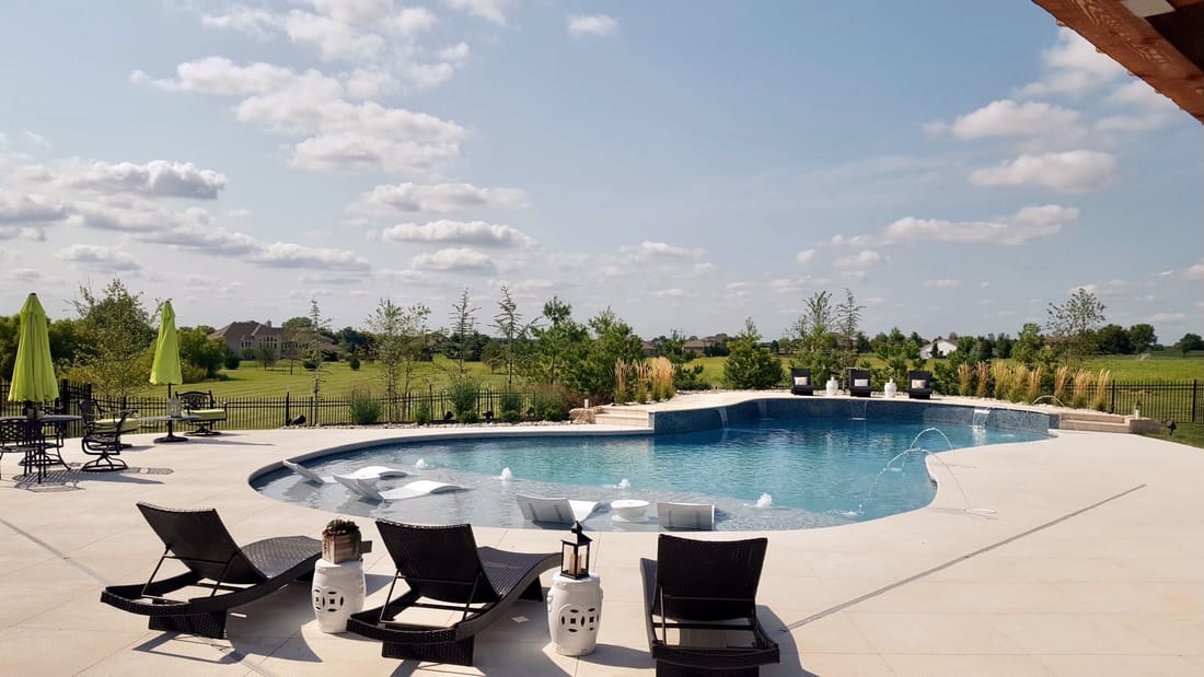 Freeform swimming pool with lounge chairs under an open sky