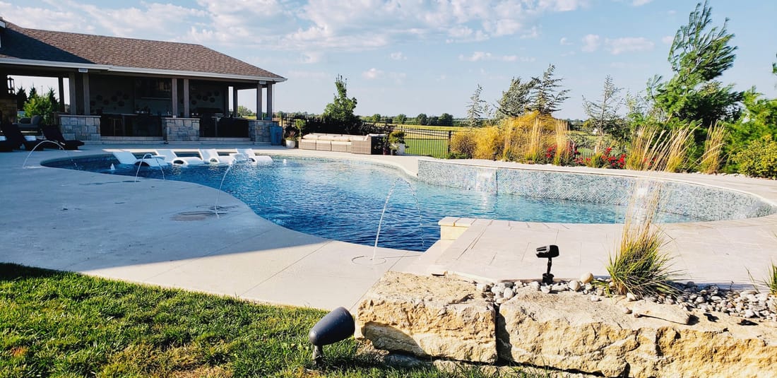 Freeform pool and patio with a covered outdoor living structure