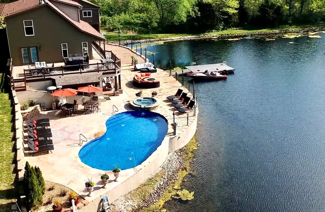 Swimming pool and patio overlooking a private lake with a dock