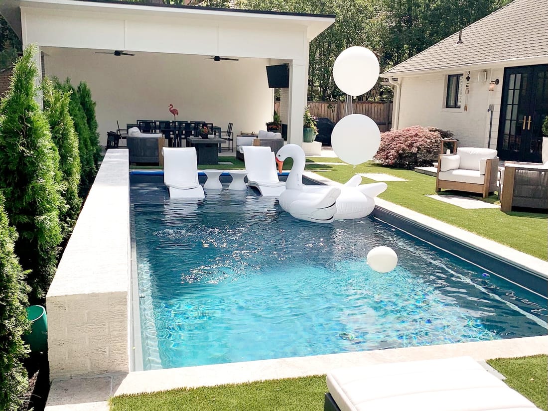 Covered outdoor living room with loungers beside a pool