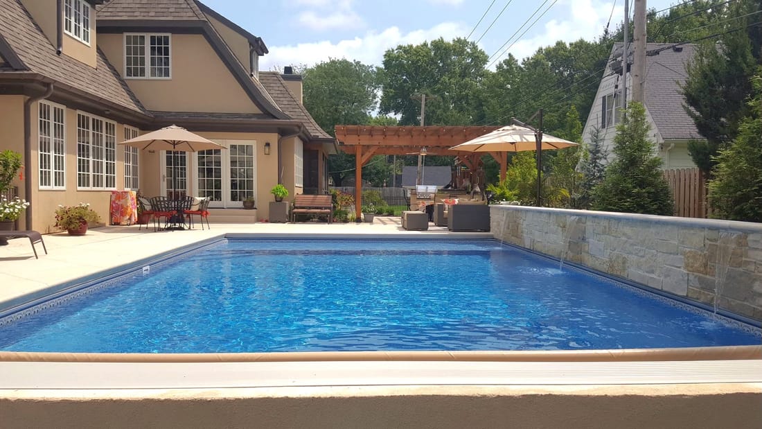 Rectangular swimming pool and pergola behind a two-story home