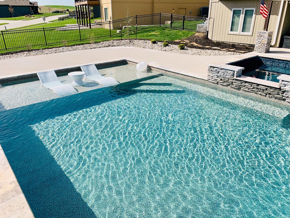 Modern rectangular pool with a tanning ledge, spa, and water wall