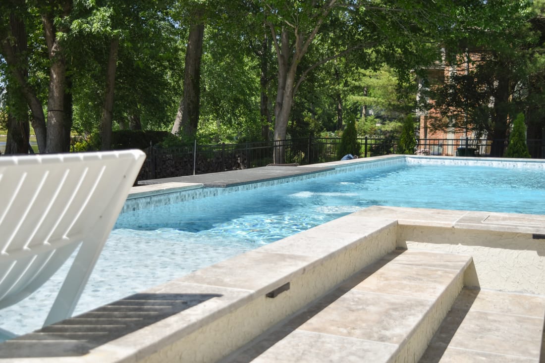 Swimming pool with a raised spa beside a shaded lawn