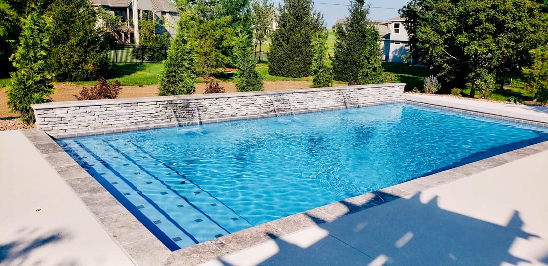 Swimming pool and spa with a pergola and landscaped surroundings