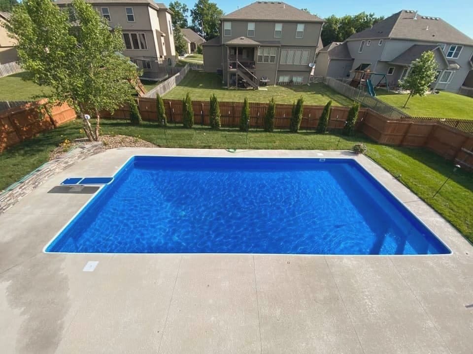 Rectangular swimming pool with a clean paver deck and lawn