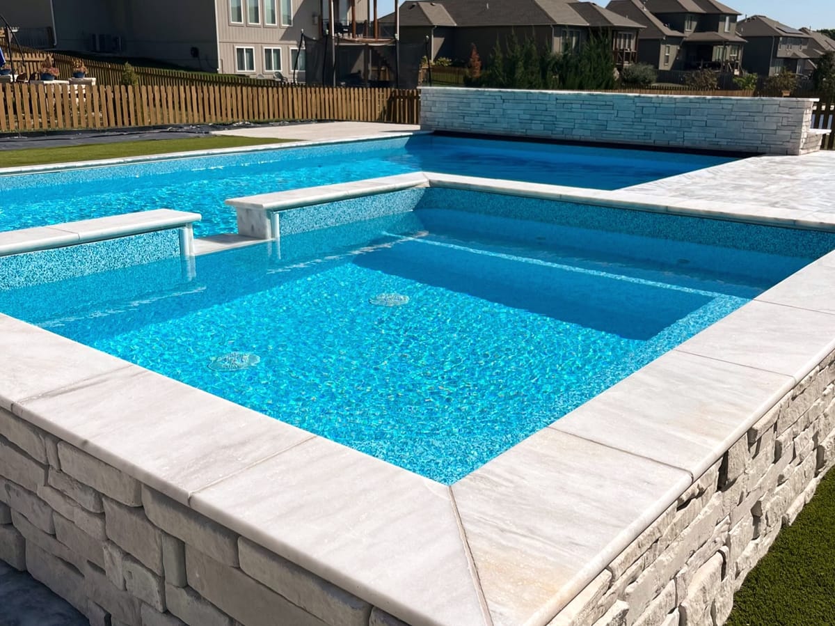 Geometric swimming pool with a raised spillover spa and a wide paver deck