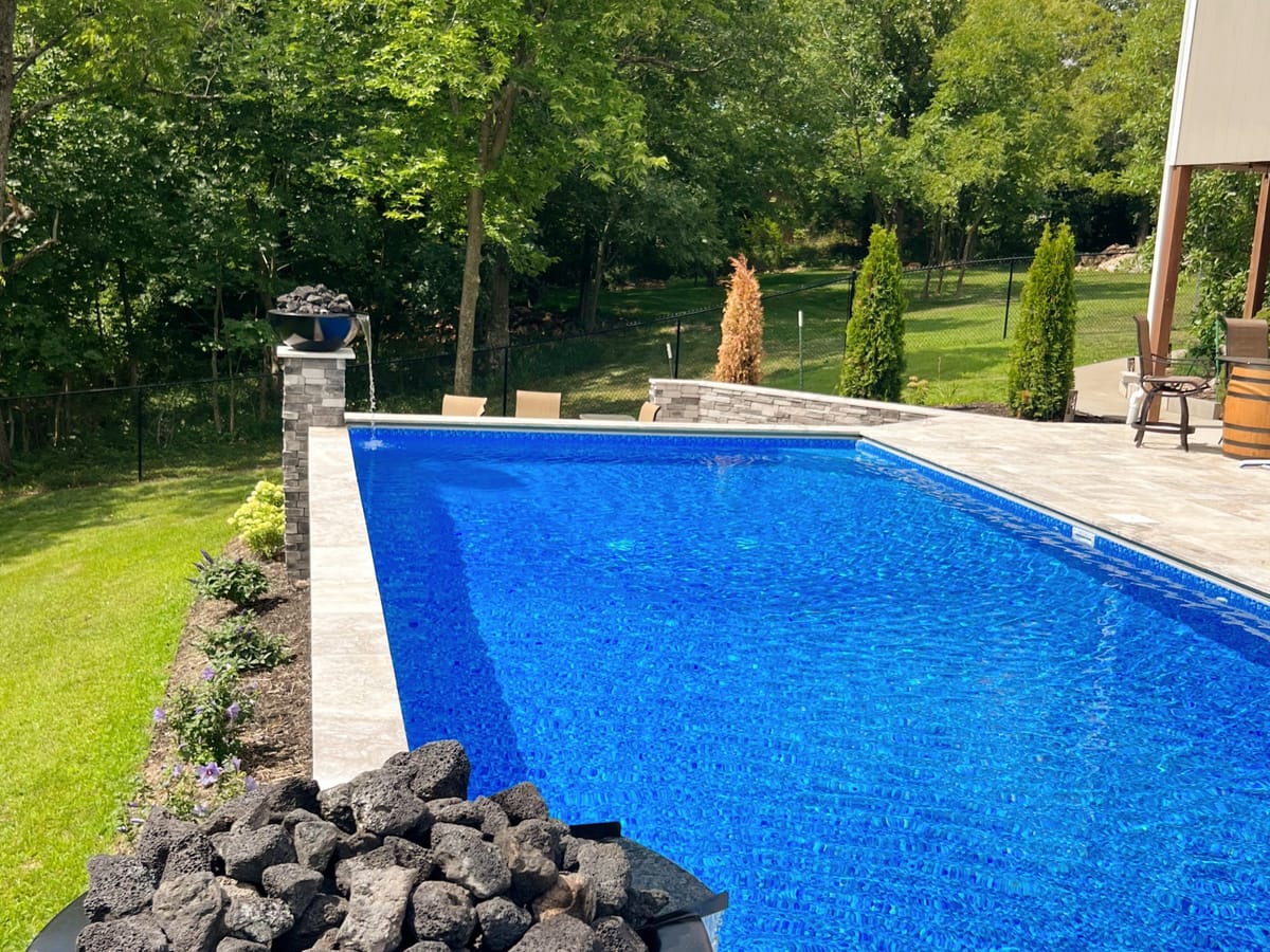 Swimming pool with a boulder retaining wall on a sloped, landscaped backyard